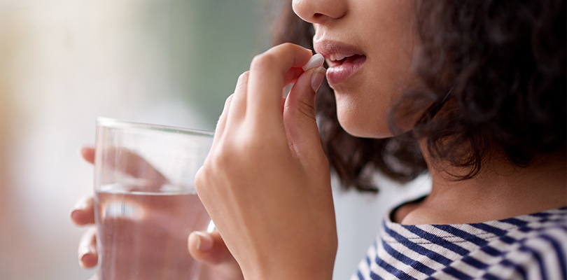 Woman taking a pill with a glass of water